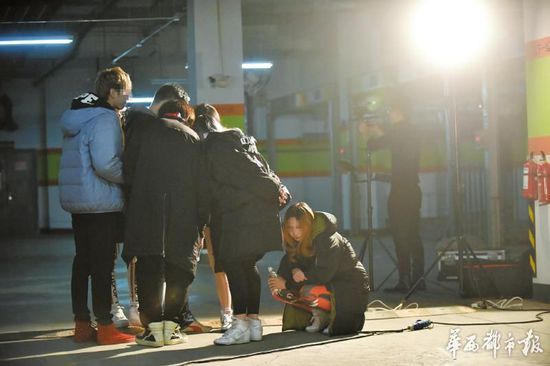 反復(fù)排練拍攝,一位女孩累得蹲在地下。